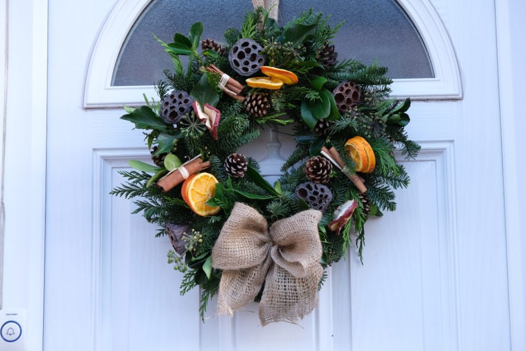 Christmas Wreath made from green foliage and natural decorations, including oranges, pine ones and cinnamon.